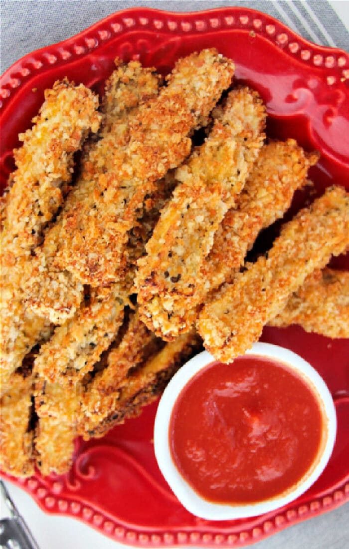 Plate of crispy breaded eggplant fries with a side of red dipping sauce.