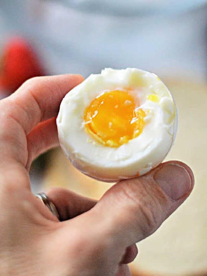 A hand delicately cradles a hard-boiled egg, its runny yolk glistening like it was perfected in a toaster oven.