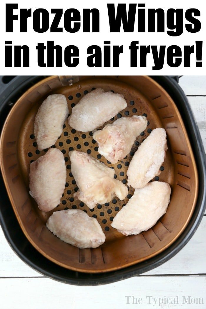 Frozen chicken wings nestled in the air fryer basket, perfectly poised to cook.