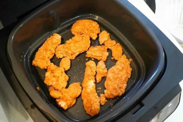 Golden-brown frozen chicken tenders in air fryer basket, perfectly crisp and ready to be served.