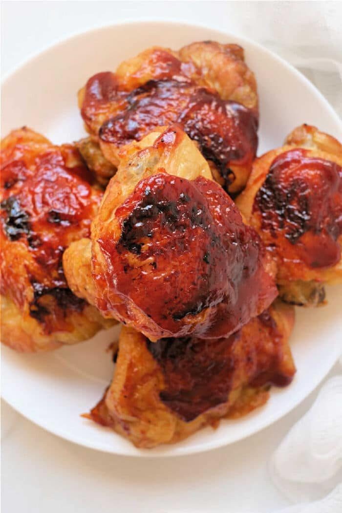 Plate of baked chicken thighs with a shiny, reddish-brown barbecue glaze on top—an easy dish to recreate using frozen chicken thighs in the air fryer for quick, good results.