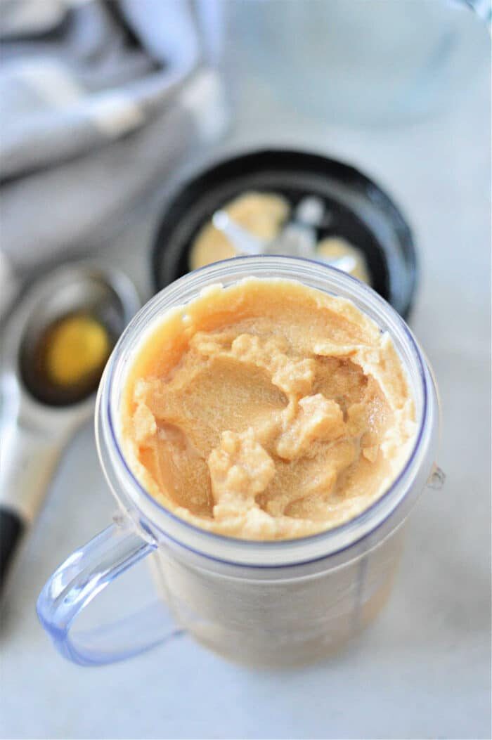 Frozen coffee in a clear container with a black lid, accompanied by an ice cream scoop nearby.