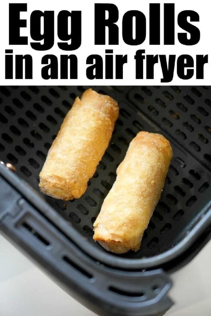 Two frozen egg rolls cooking in an air fryer basket, with text reading Egg Rolls in an air fryer above.