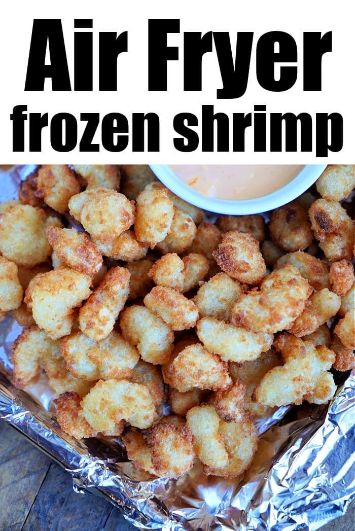 A pile of crispy frozen popcorn shrimp sits on foil, topped with a small bowl of dipping sauce. The text above reads Air Fryer frozen shrimp.