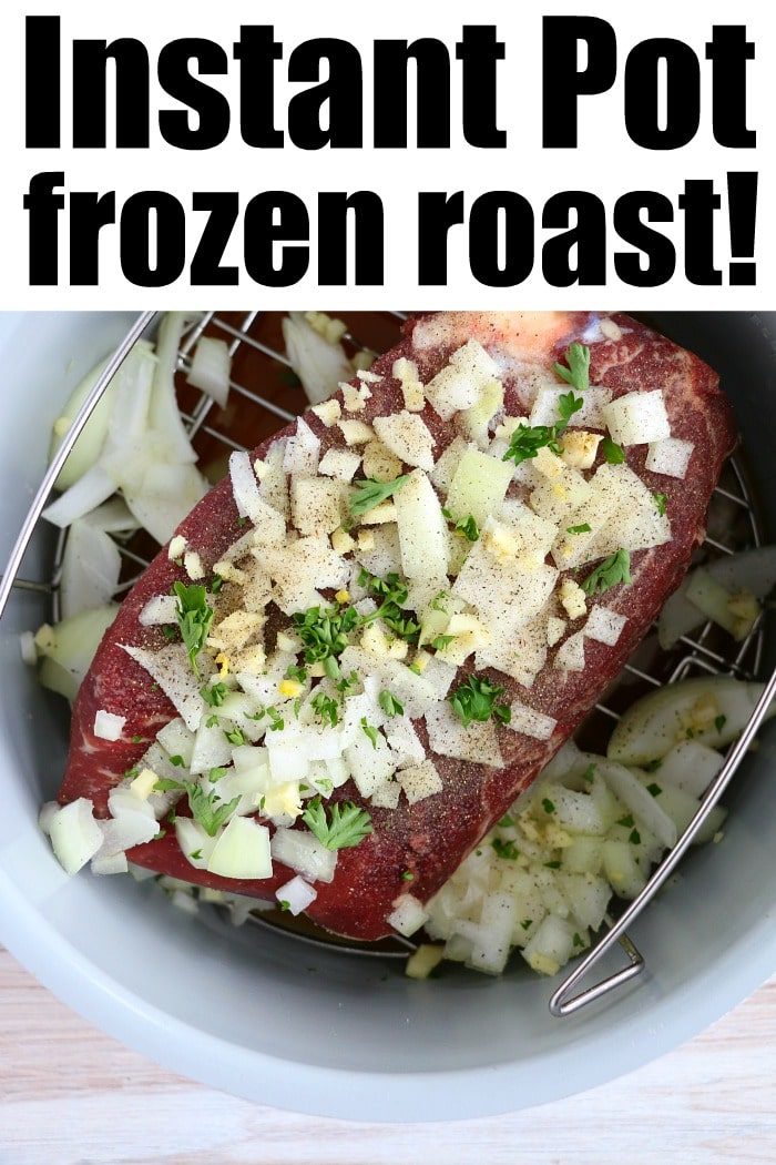 A raw frozen roast covered with chopped onions, garlic, and herbs sits inside an Instant Pot on a metal trivet. The caption reads "Frozen roast in Instant Pot magic!
