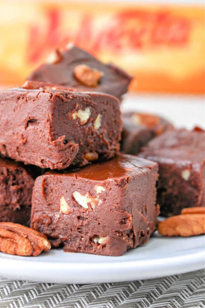 Close-up of chocolate fudge with Velveeta and pecan pieces stacked on a plate.