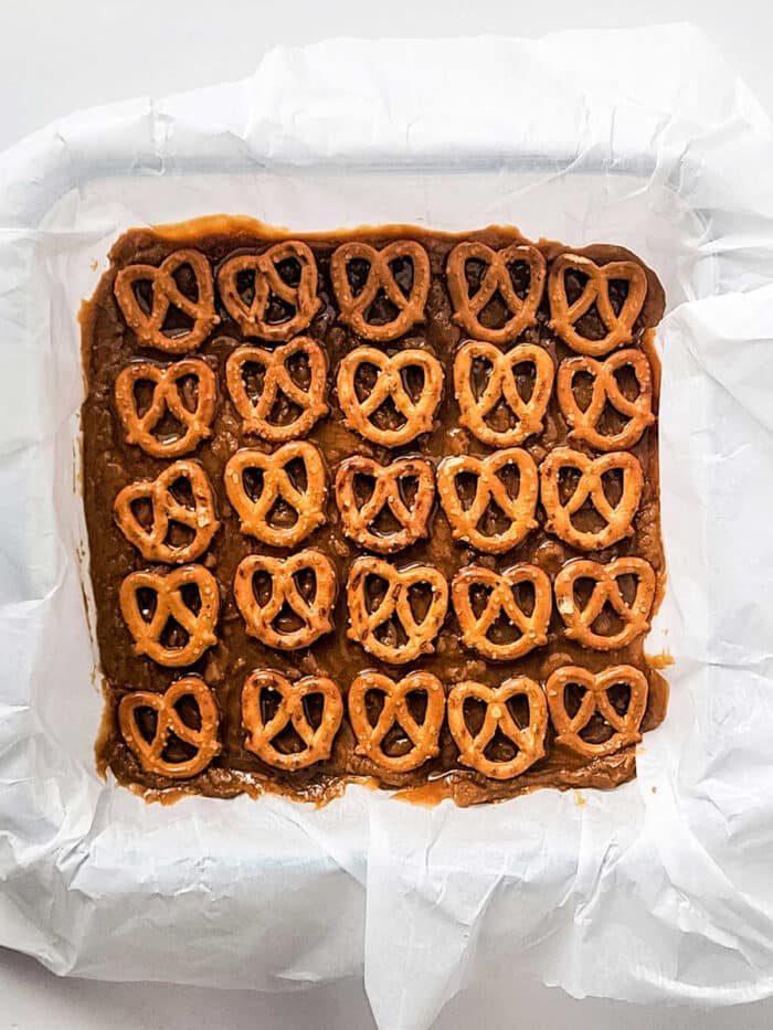 Square pan with Grandma's old fashioned topped with a grid of pretzels on parchment paper.