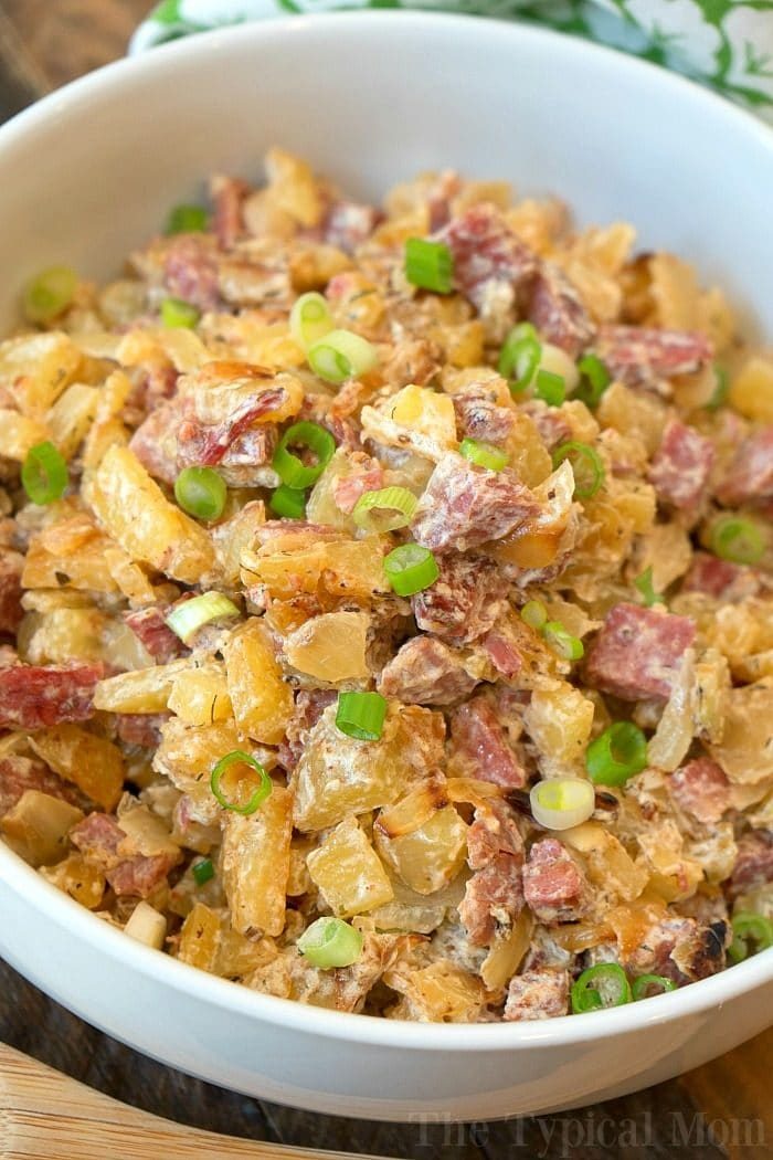 A bowl of creamy classic corned beef hash, topped with chopped green onions.