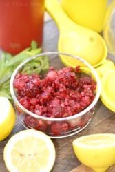 Bowl of crushed raspberries and fresh lemons ready for the juicer, solid for crafting homemade raspberry lemonade on a rustic wooden surface.