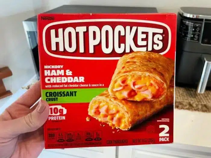 A person is holding a box of Hot Pockets.