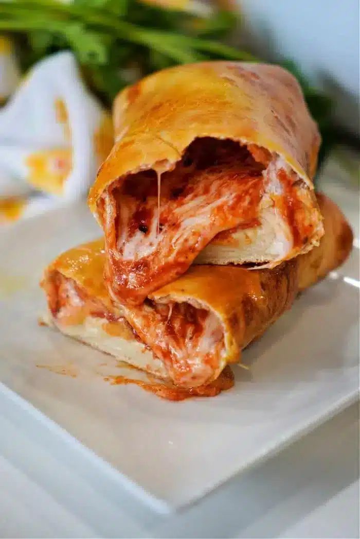 A close-up shot of two slices of stromboli stacked on a white plate.