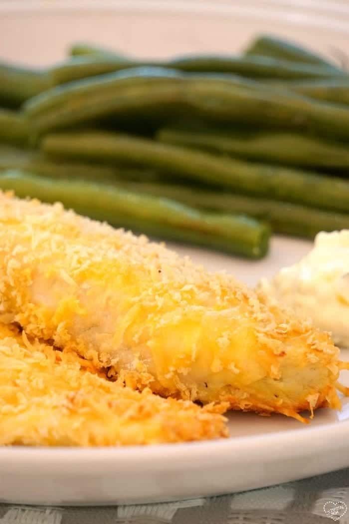 Breaded fish with a side of green beans and a dollop of sauce on a plate, ready in the time it takes to cook cod to perfection.