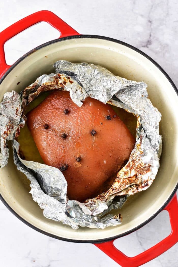 pork roast with cloves wrapped in foil, nestled in a red-handled pot on a marble countertop, evokes the warmth of knowing how long to cook pork roast in the oven at 375 for that solid dinner.