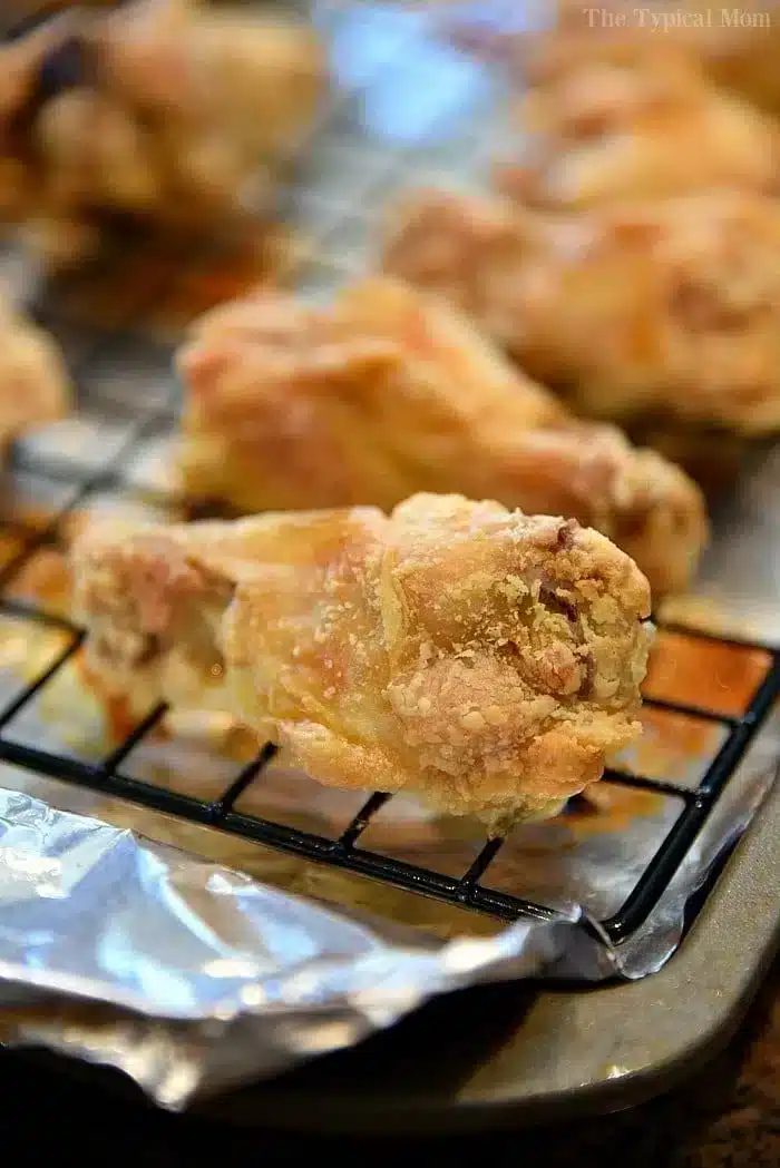 Several chicken wings rest on a cooling rack. The chicken wings are lightly browned and appear to be oven-baked or fried.