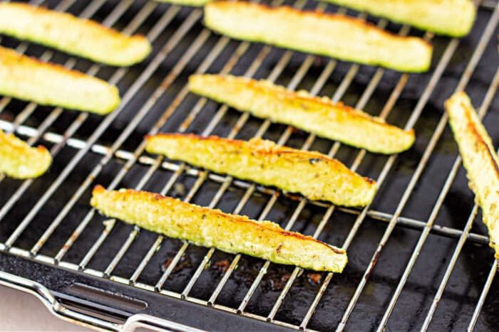 Close-up of zucchini fries on a baking sheet, lightly browned and evenly spaced, offering a hint of deliciousness for those curious about how long to roast zucchini to perfection.