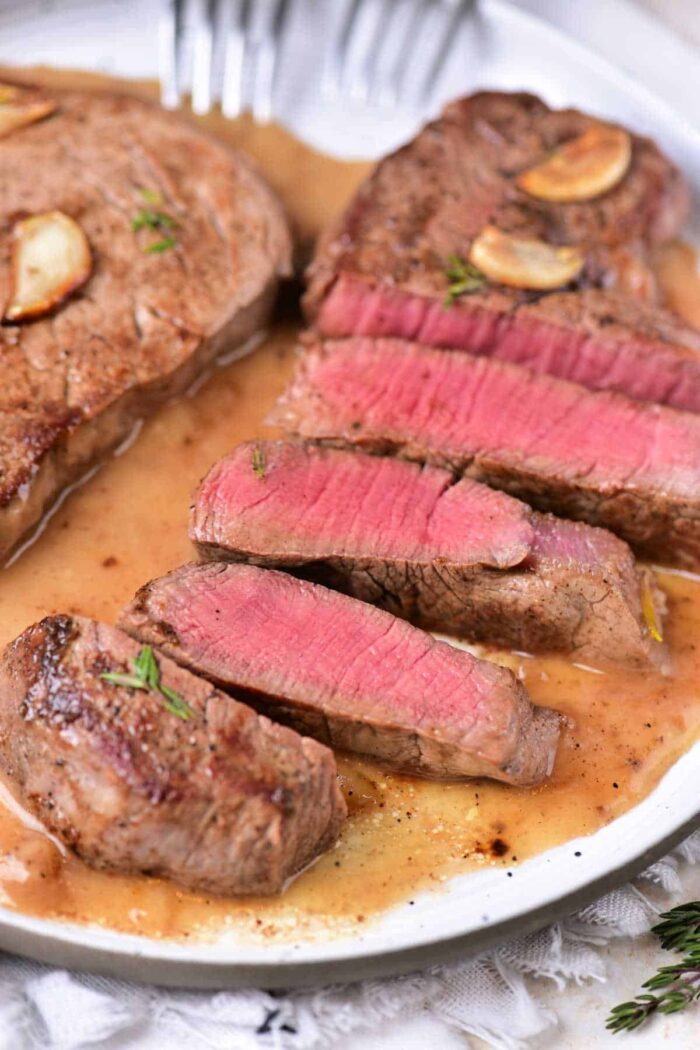 Sliced medium-rare with garlic and herbs beef tenderloin medallions.