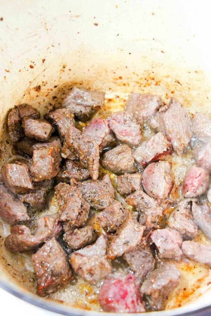 Chunks of beef browning in a pot with juices and seasoning visible around the meat—a solid start if you're wondering how to cook beef tips for a flavorful meal.