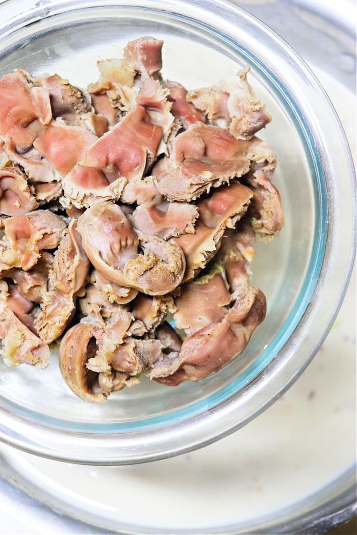 A glass bowl filled with cooked chicken gizzards, seen from above—solid for learning how to make gravy from chicken drippings.