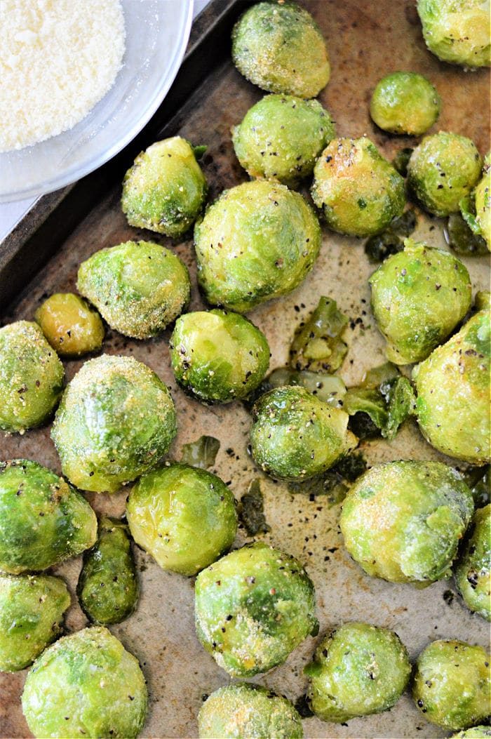 Discover how to cook frozen Brussels sprouts by roasting them to perfection, seasoned with a medley of spices on a baking tray.
