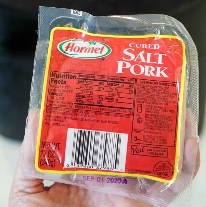 A hand holds a sealed package of Hormel cured salt pork with a nutrition label and a best by date of Sep 01 2023, solid for those learning how to cook pork belly in the oven.