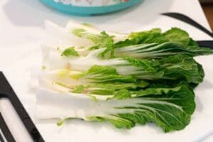 Fresh bok choy, washed and halved, displayed on a white cutting board—solid for learning how to make bok choy dishes at home.