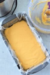 Next to a bowl with leftover batter, the wax paper-lined loaf pan holds potential for a good creation—like when you learn how to make Velveeta cheese sauce, transforming simple ingredients into something irresistible.