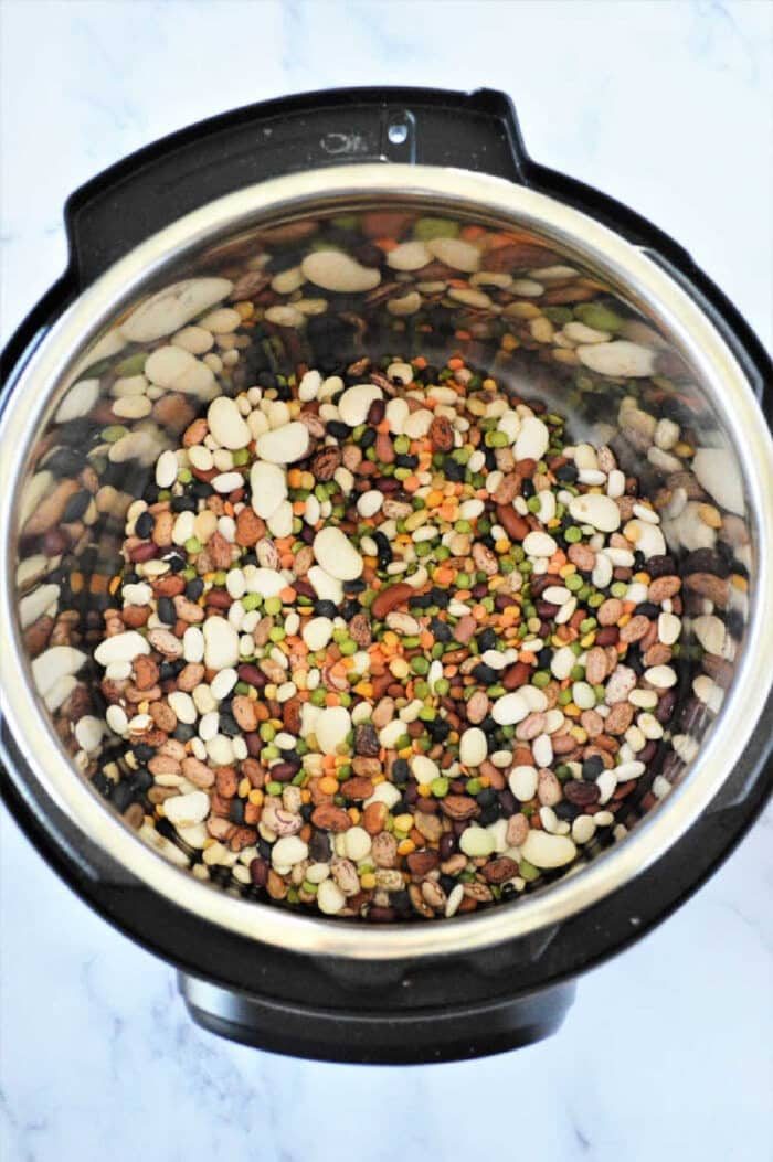 Instant Pot 15 bean soup sits invitingly on a marble countertop, showcasing its hearty mix of flavors and rich textures.