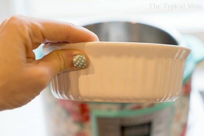 A hand with polka dot nail art holds a white ceramic bowl in front of a colorful kitchen appliance, showcasing stylish instant pot accessories.