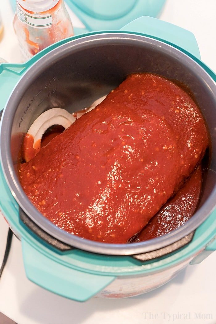 chuck roast topped with sauce sits deliciously inside a pressure cooker on the countertop, reminiscent of comforting instant pot beef roast recipe.