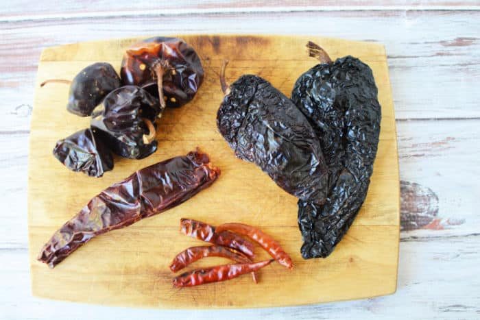 Assorted dried chili peppers arranged on a wooden cutting board, solid for adding bold flavor to Instant Pot Birria Tacos.