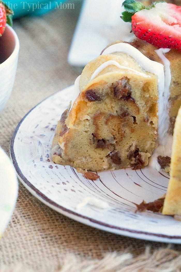 A slice of decadent bread pudding with white icing sits gracefully on a decorative plate, crowned with sweet strawberry slices—a delightful treat that rivals even the richest instant pot bread pudding.