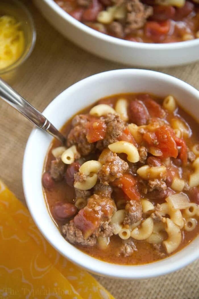 A bowl of goulash featuring macaroni, ground beef, tomatoes, and beans, with a spoon in the bowl—solid for those craving an easy instant pot chili mac recipe.