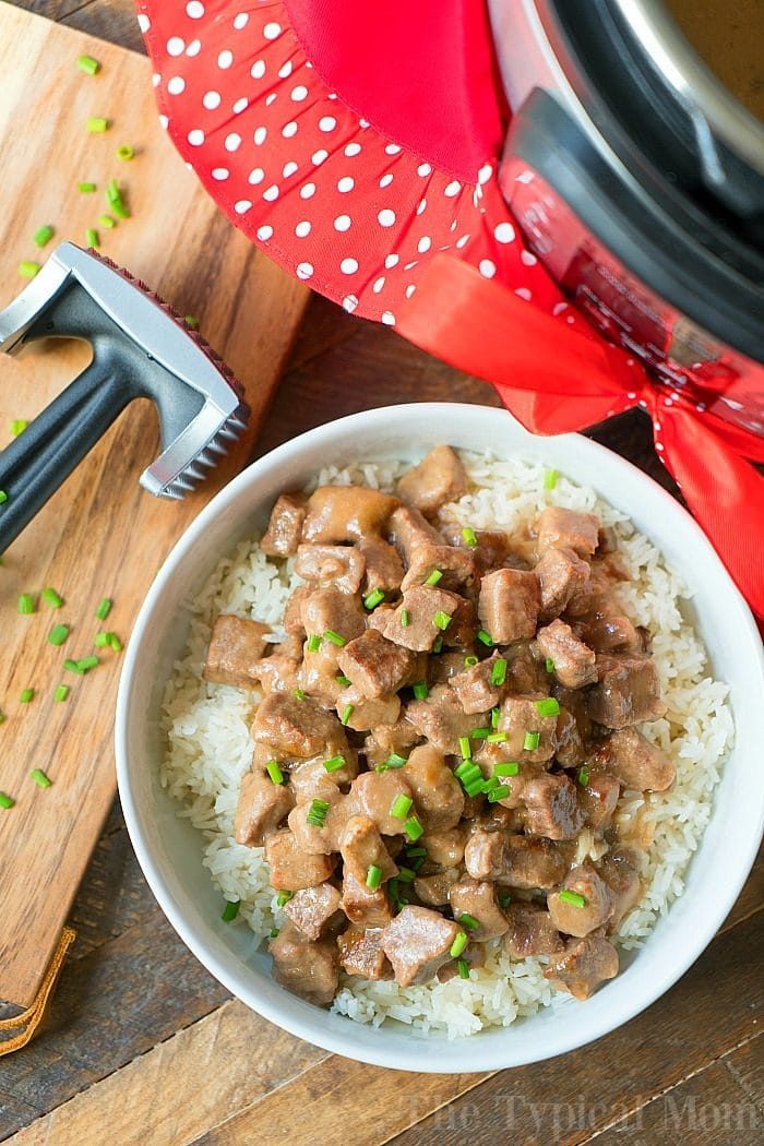 A bowl of savory beef steak with rice, garnished with chives, sits invitingly next to a meat tenderizer and an Instant Pot—solid for when youre craving that cube steak tenderness.