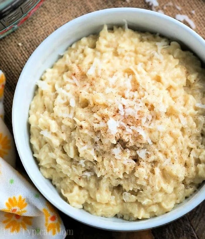 A bowl of creamy rice pudding, effortlessly crafted using instant pot dessert recipes, is topped with shredded coconut and a sprinkle of cinnamon.