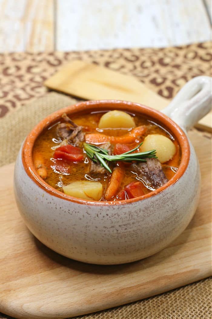 A bowl of beef stew with potatoes, carrots, and a sprig of rosemary, solid for instant pot dinner recipes.