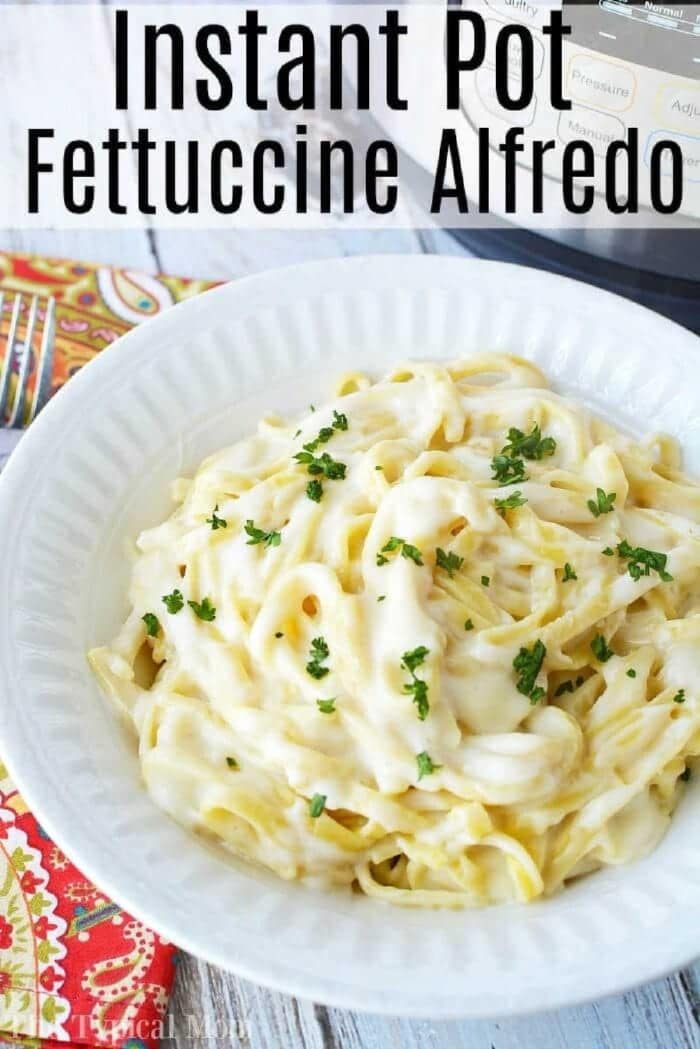 A white bowl of creamy Instant Pot fettuccine Alfredo topped with parsley, with an Instant Pot in the background.
