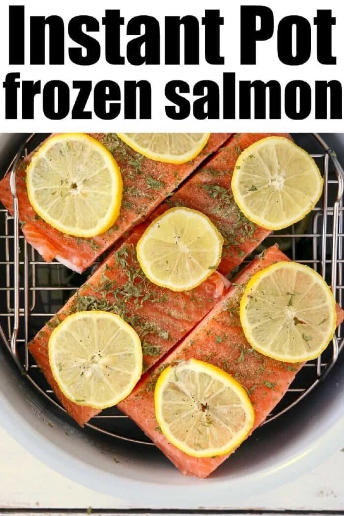 Four pieces of instant pot frozen salmon topped with lemon slices and herbs, arranged in the basket and ready to cook.