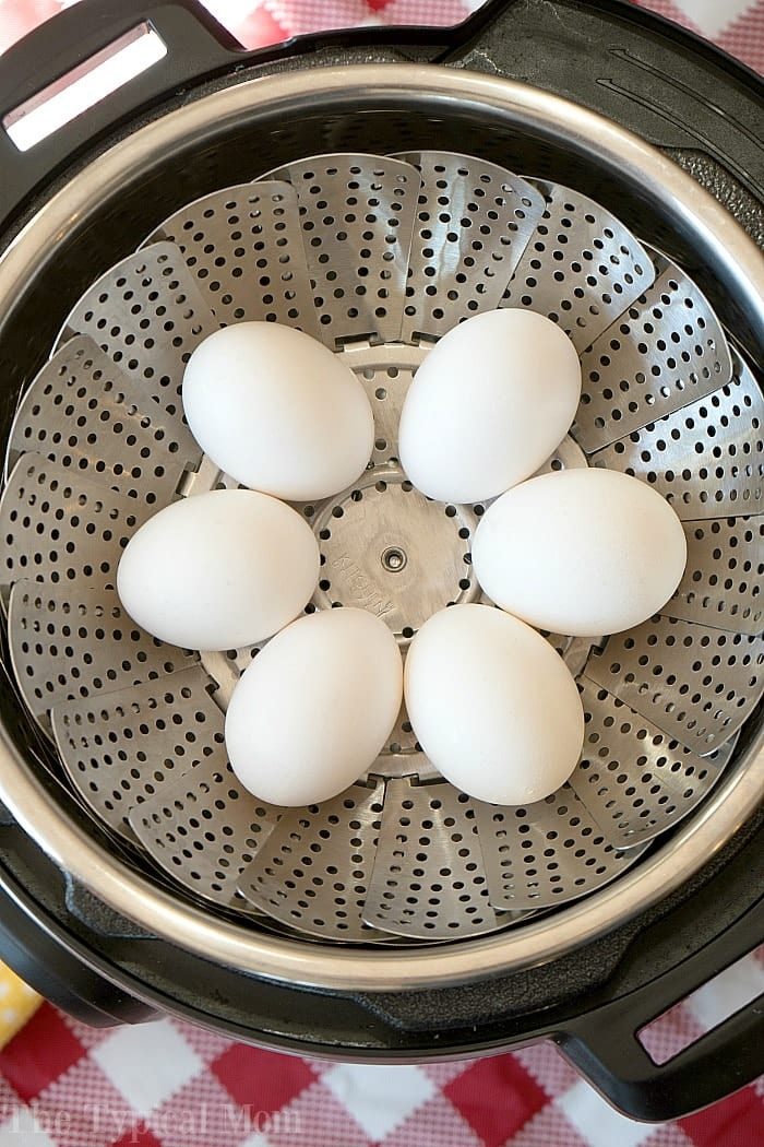 Six white eggs rest on a metal steamer basket inside an Instant Pot, ready to be transformed into an easy instant pot potato salad.