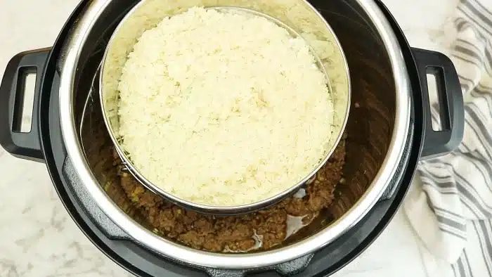 Overhead view of rice in a bowl stacked over instant pot Korean beef on a marble surface.