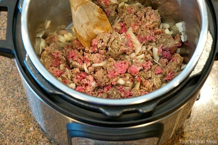 Ground beef and chopped onions are being cooked to perfection in an Instant Pot