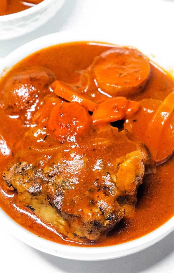 A bowl of Instant Pot Oxtail Soup with tender oxtail, carrots, and potatoes simmered in a rich red sauce.