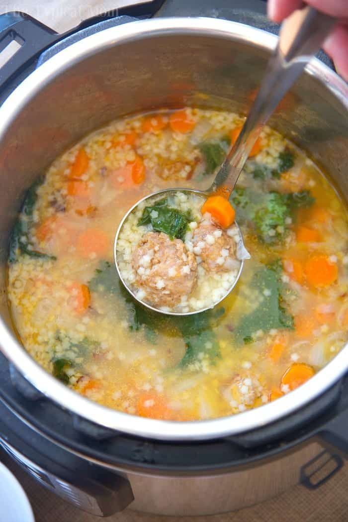 A ladle lifts meatball and vegetable soup from an Instant Pot, showing carrots, greens, and pasta—solid inspiration for instant pot soup recipes.