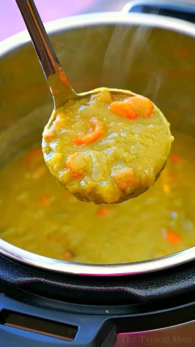 A ladle scoops thick Instant Pot Split Pea Soup Recipe with carrots from an Instant Pot.