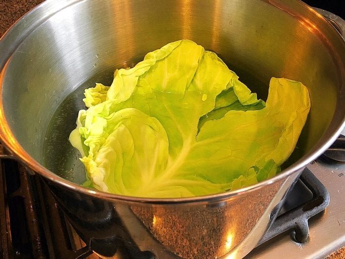 A cabbage leaf simmers gently in a stainless steel pot on the stove