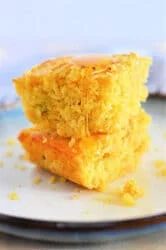 Two pieces of Jiffy Mexican Cornbread stacked on a plate, drizzled with honey.