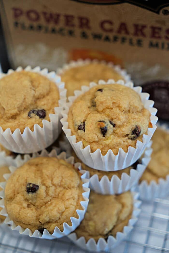 A stack of Kodiak Muffins in white paper liners sits in front of a box of pancake mix, tempting you with every chocolate chip.