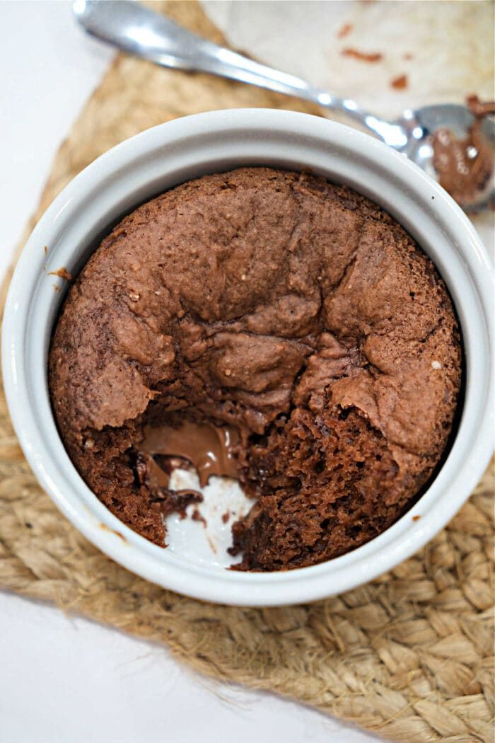 Chocolate lava cake in a white ramekin with a spoonful missing, revealing gooey melted chocolate inside—solid for those who love the rich, decadent flavor of homemade treats like Chocolate Banana Bread.