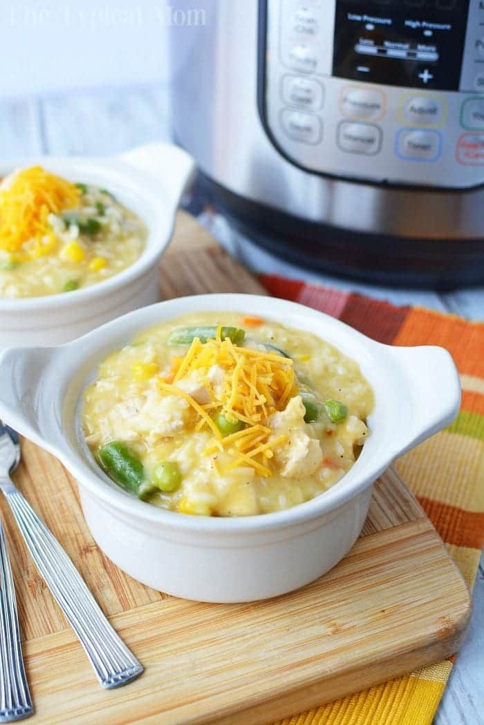 A warm bowl of creamy chicken and vegetable soup made from leftover chicken breast, topped with cheese. An Instant Pot sits in the background, hinting at a convenient approach to good leftover chicken breast recipes.