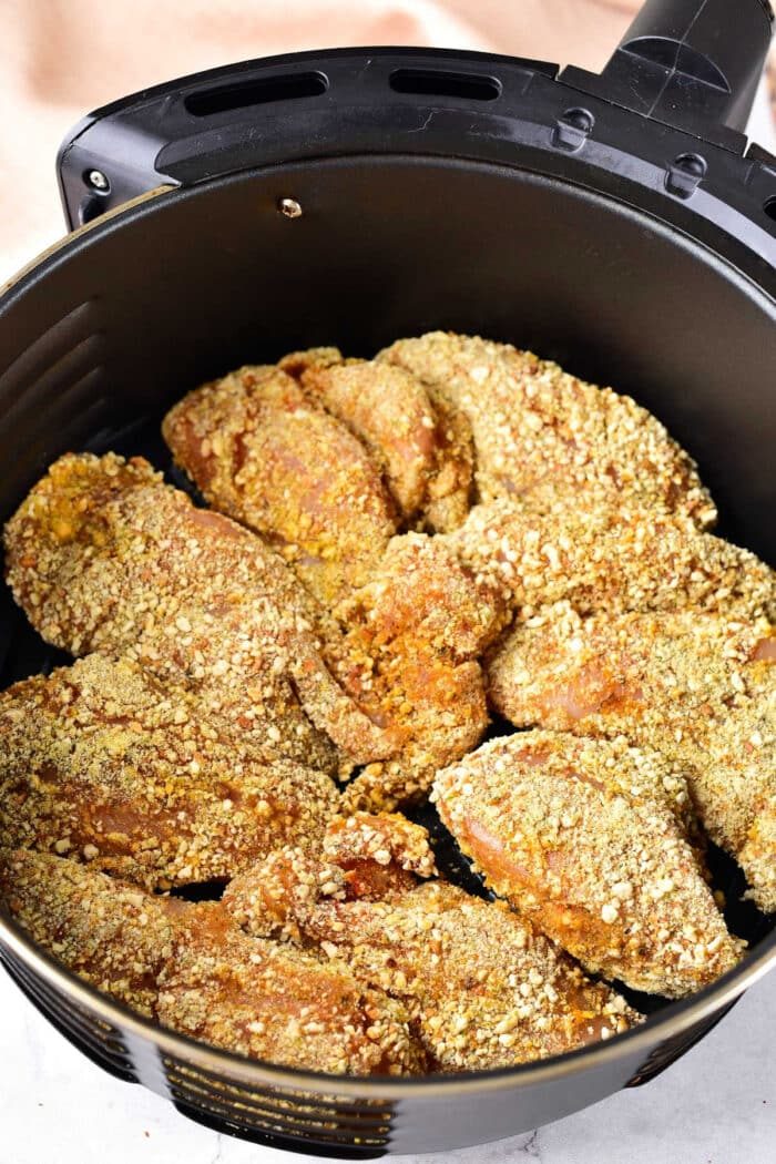 Breaded chicken pieces in an air fryer basket, ready to be cooked to crispy perfection, make a delightful pairing with your favorite leftover cornbread recipes.