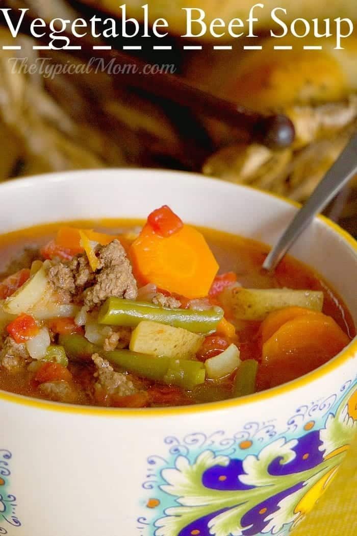 A bowl of vegetable beef soup with carrots, green beans, beef, and tomatoes sits with a spoon in the bowl—solid inspiration for leftover meatloaf recipes.